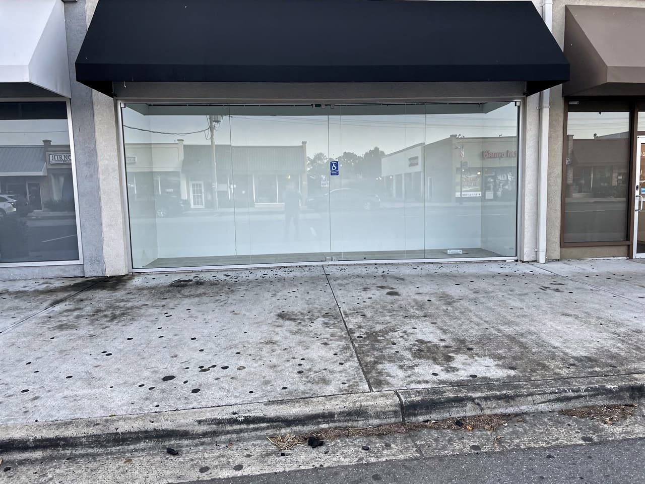 A storefront entry sidewalk dotted with gum and grime before washing