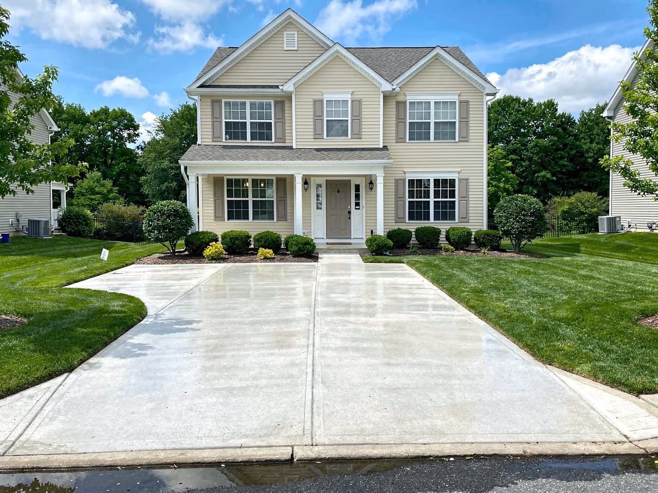 A freshly washed home with clean siding and bright, spotless driveway concrete